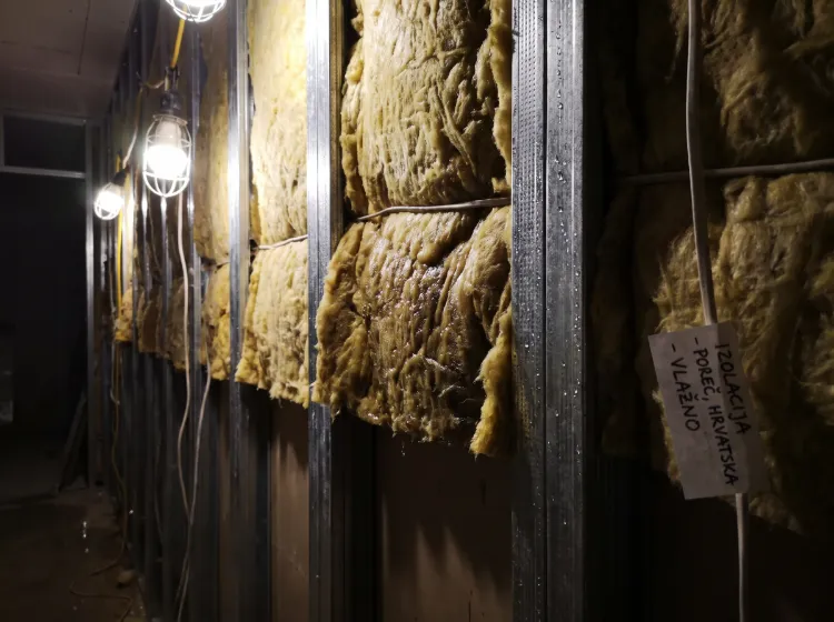 Mokra žuta mineralna vuna unutar metalne potkonstrukcije pregradnog zida s vidljivim kapljicama vode