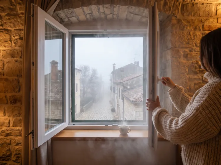 Osoba pokušava provjetriti sobu otvaranjem prozora dok je vani gusta magla